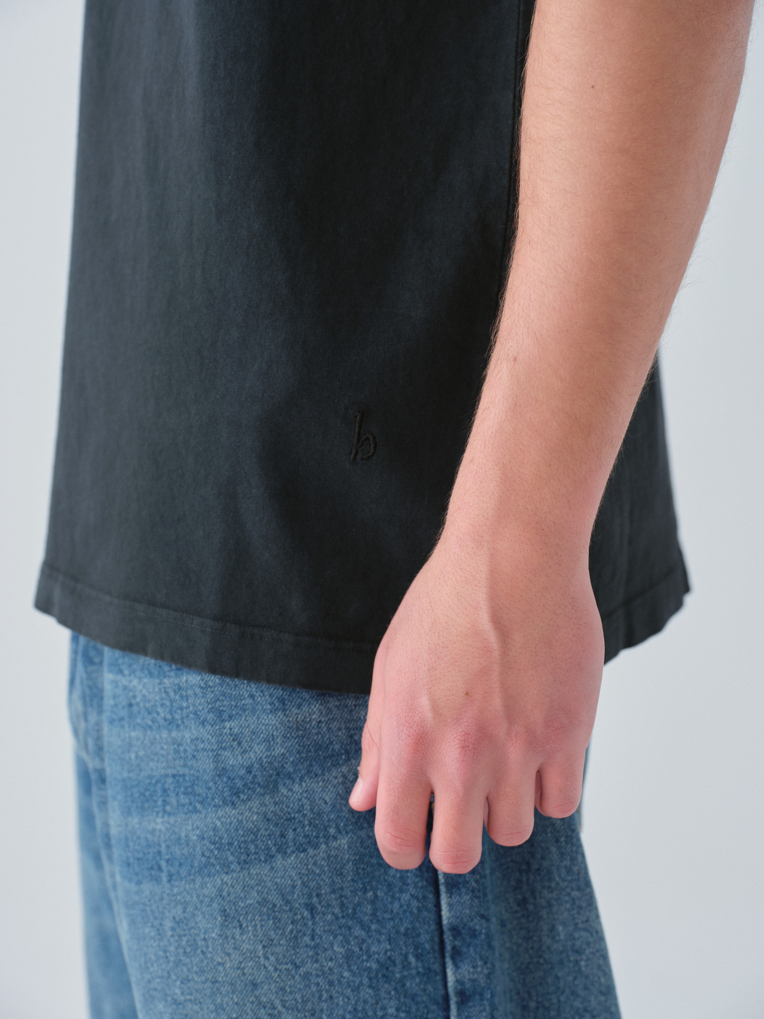 Model wearing Sunwashed Staple T-Shirt in vintage black close up detail