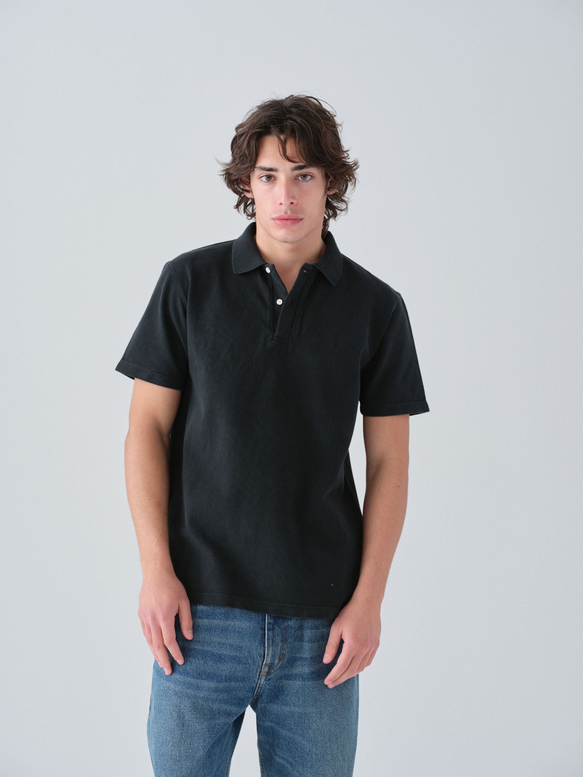 Model wearing a Sunwashed Staple Polo Shirt in vintage black color