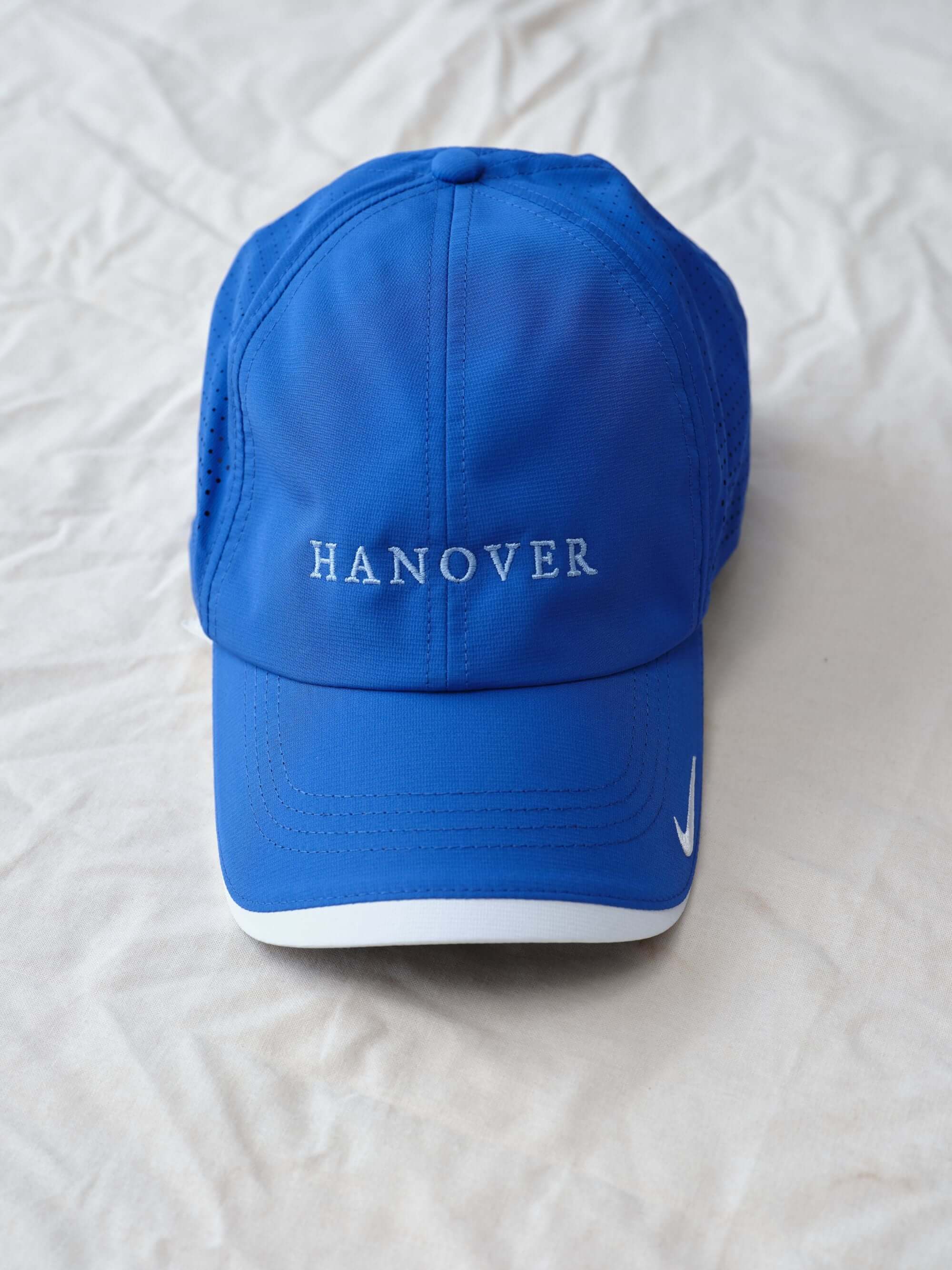Hanover Performance hat in royal with 'Hanover' embroidery on a white textured background