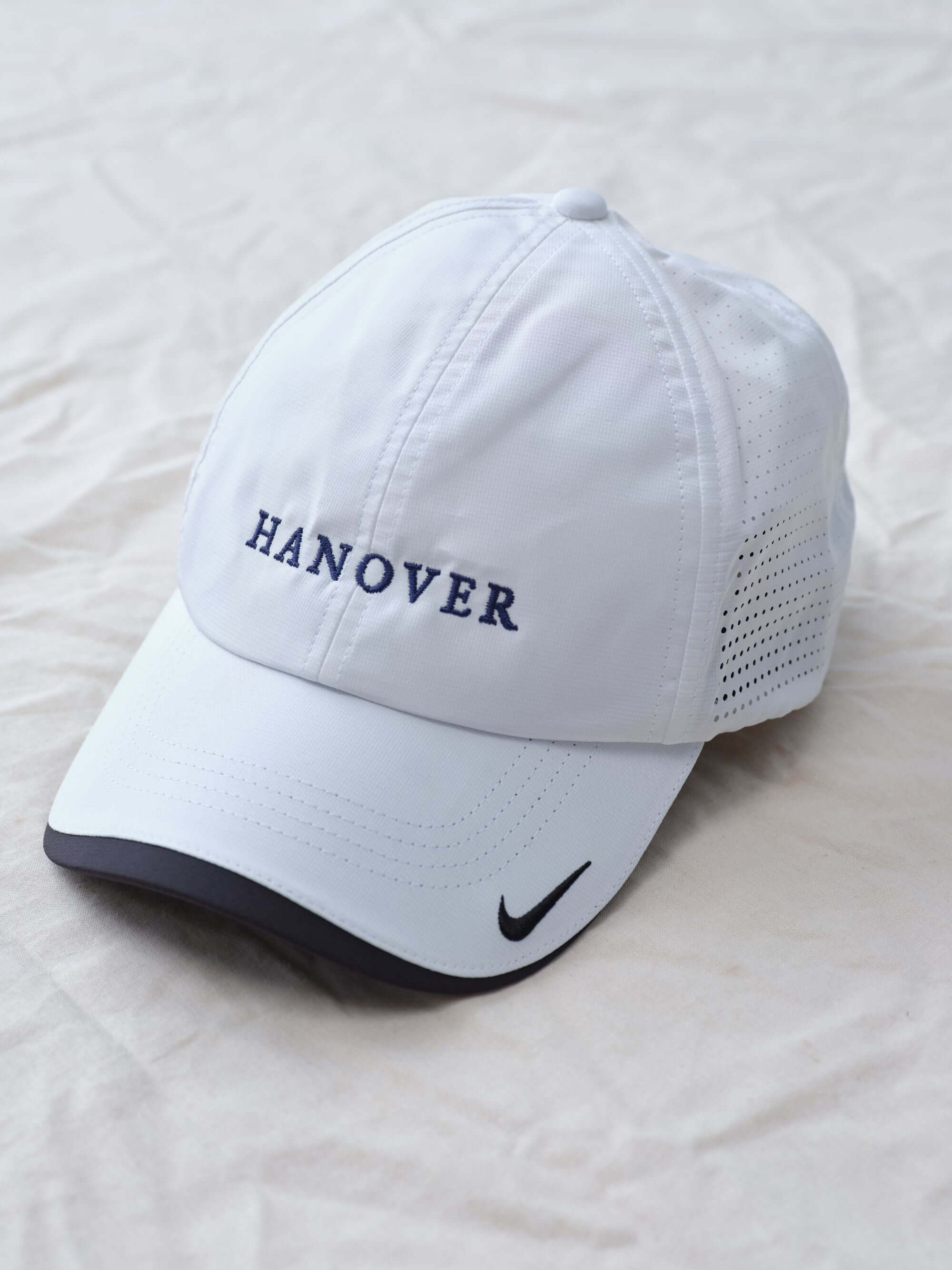 Hanover Performance hat in white with 'Hanover' embroidery on a white textured background alternate side view