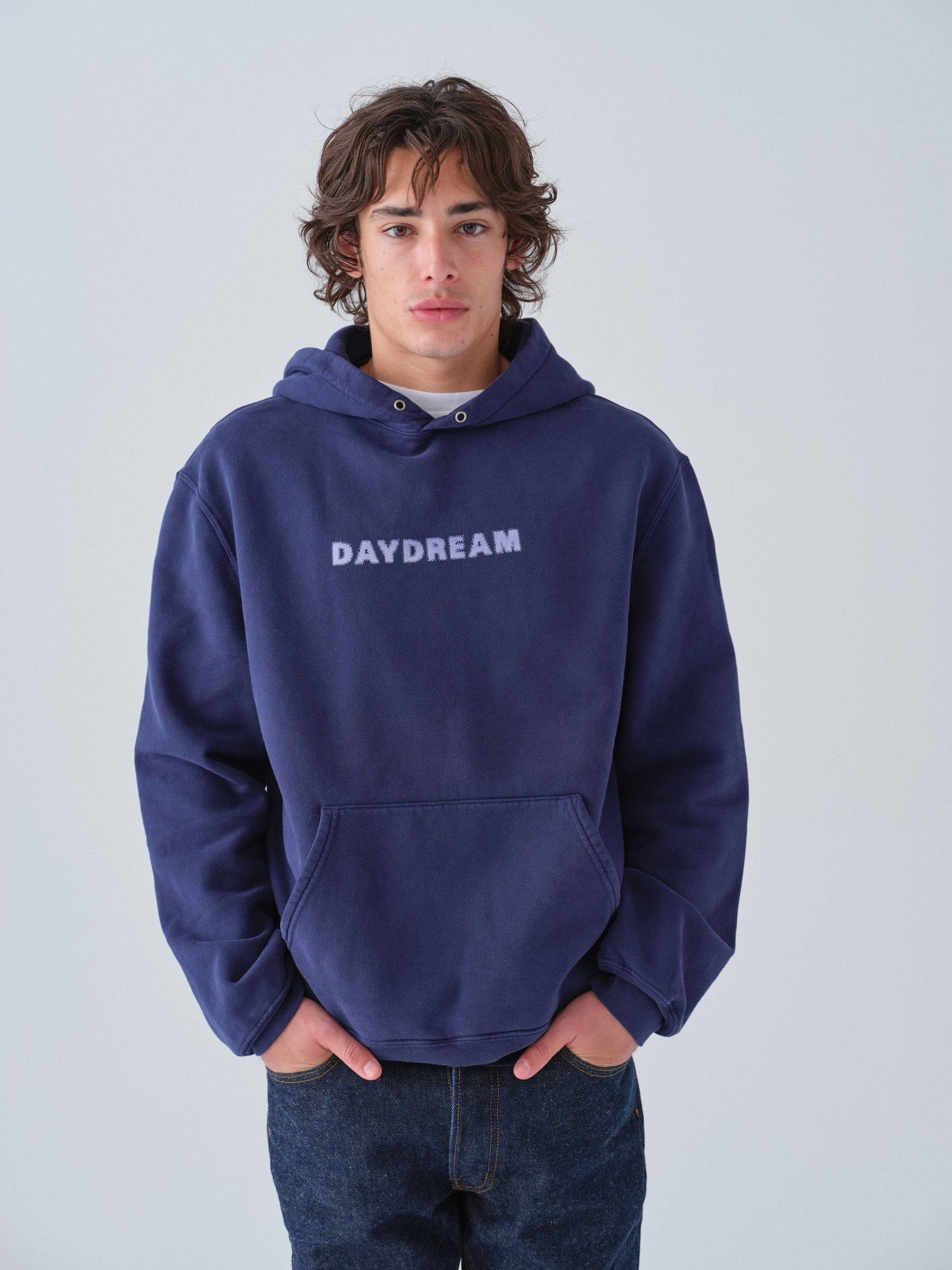 Person wearing a navy hoodie with 'DAYDREAM' text on a light gray background