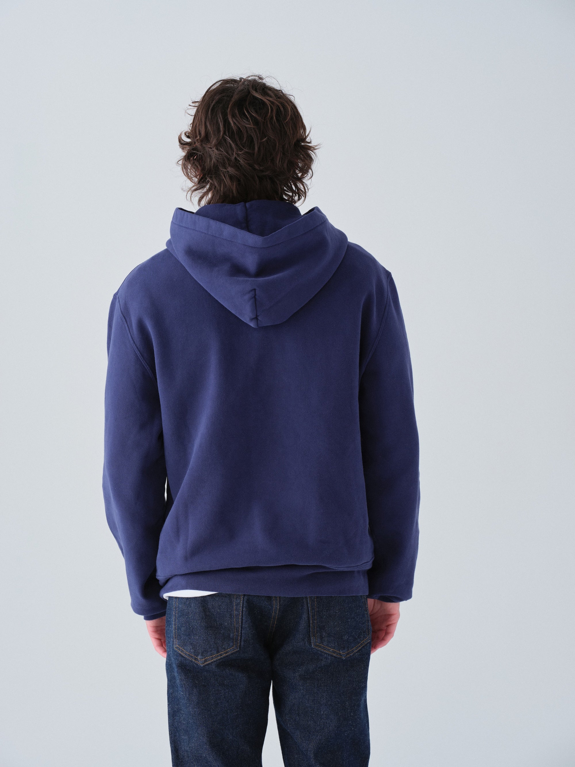 Person wearing a blue hoodie from behind on a plain background