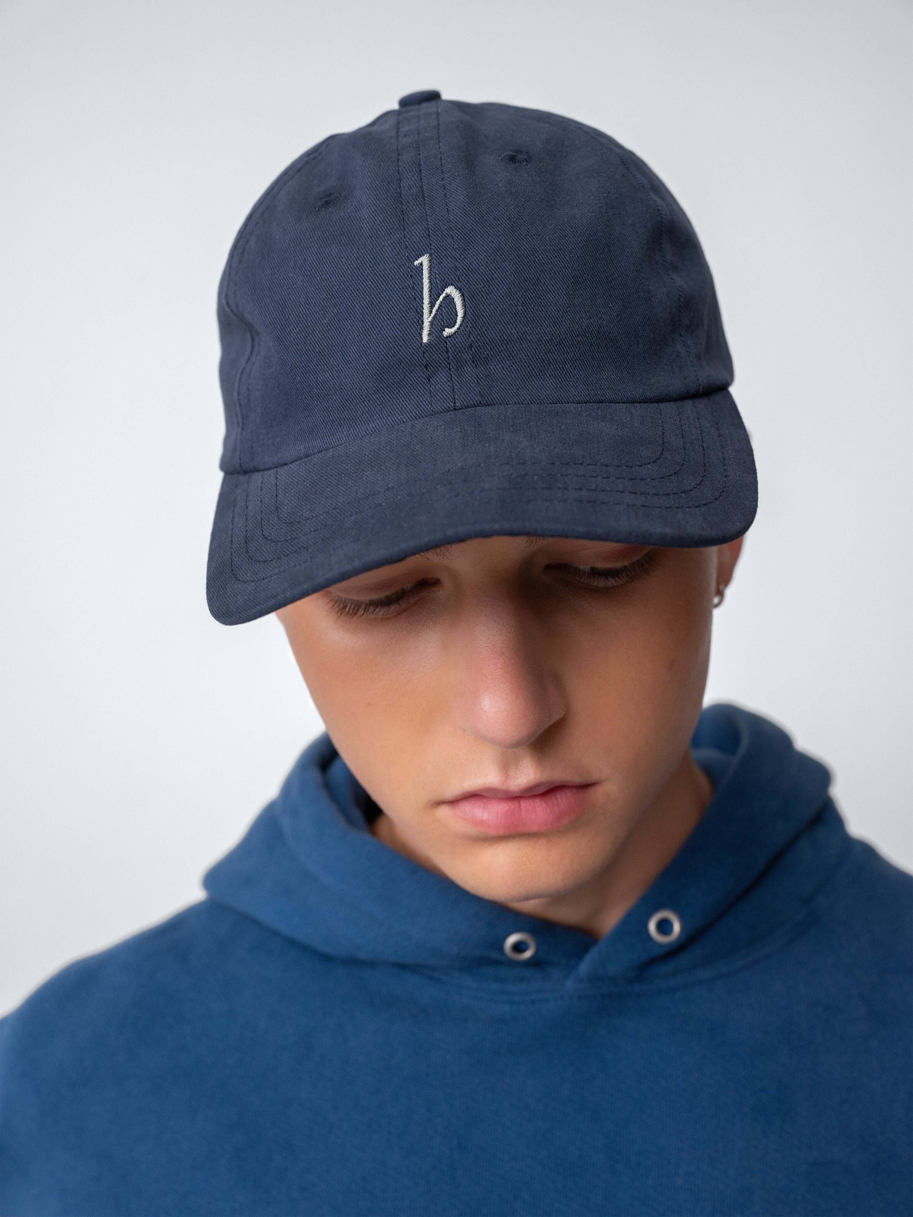 Hanover Cap in dark navy cotton twill, featuring embroidered logo, worn by a model.