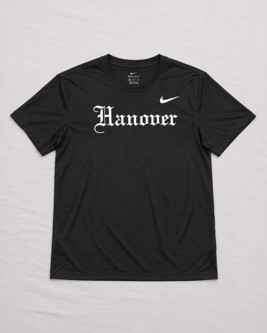 A black short-sleeve t-shirt with 'Hanover' printed in a white Gothic font across the chest,, laid flat on a light gray background.