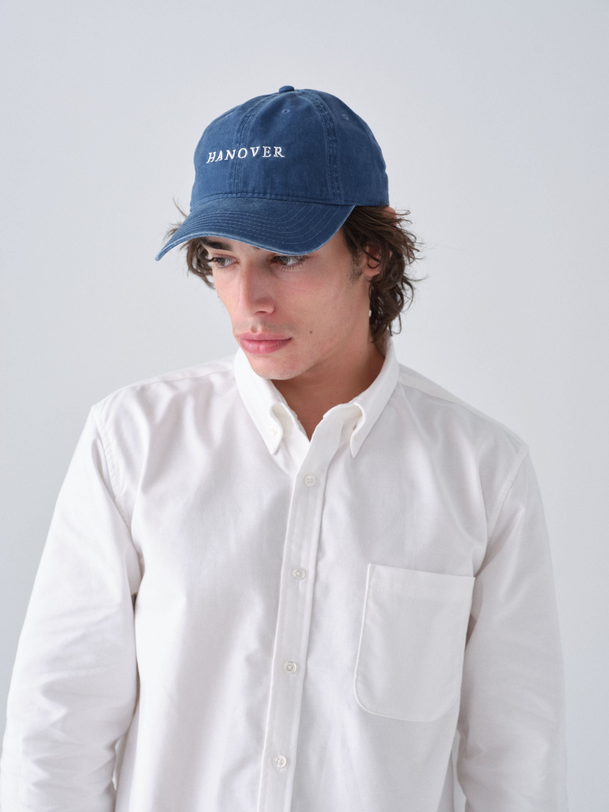 Person wearing a navy blue cap with 'HANOVER' text on a plain background