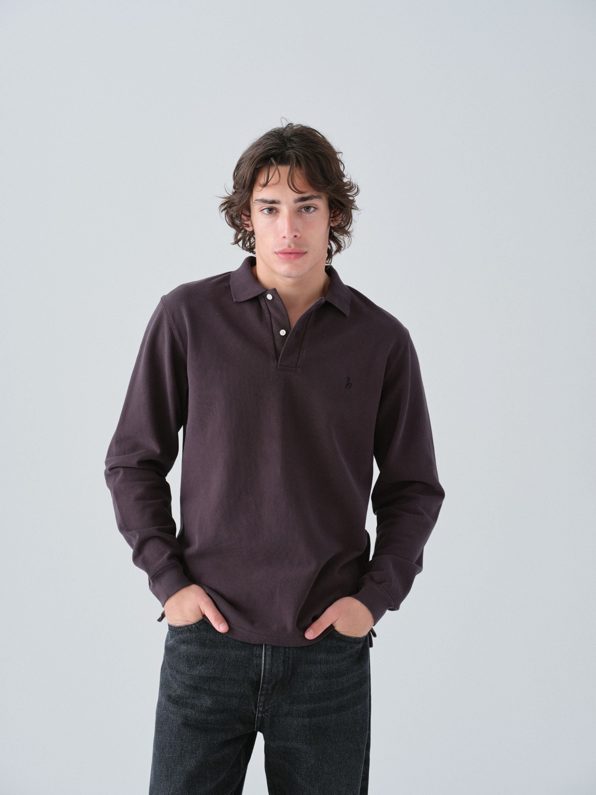 Hanover model wearing a dark brown long-sleeve polo shirt against a light gray background
