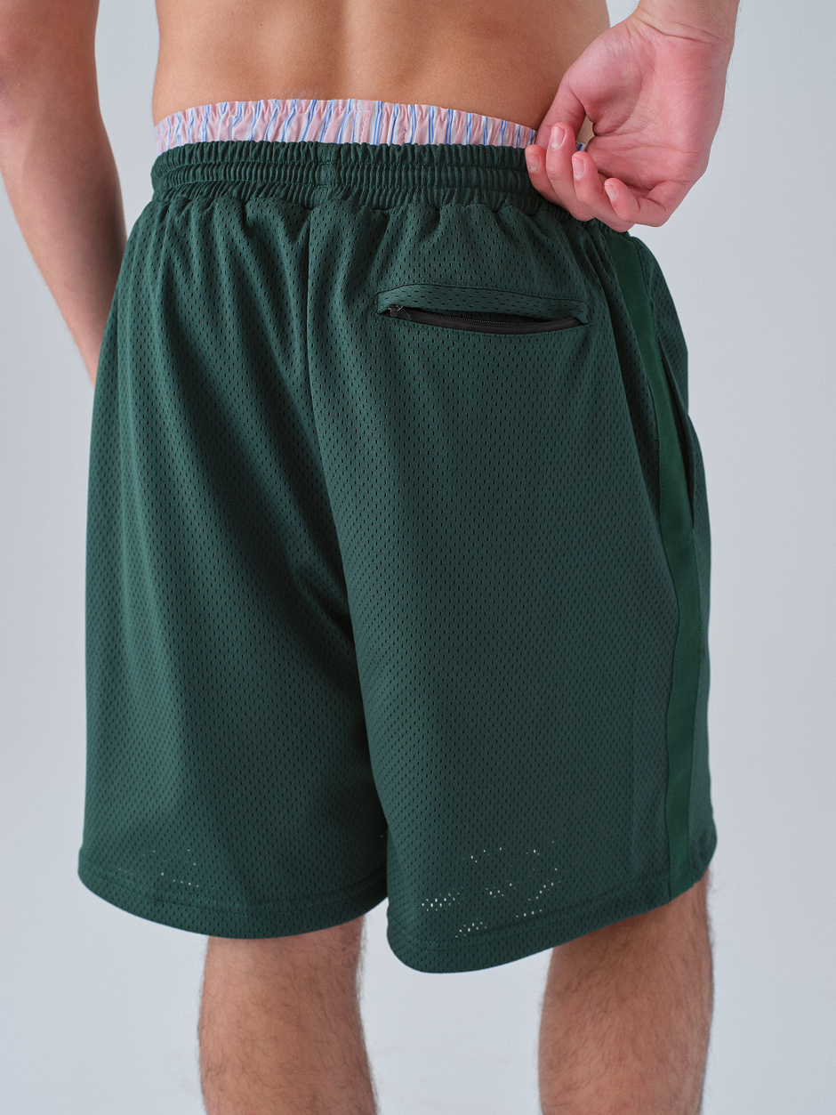 Green athletic shorts with a pocket on a plain background