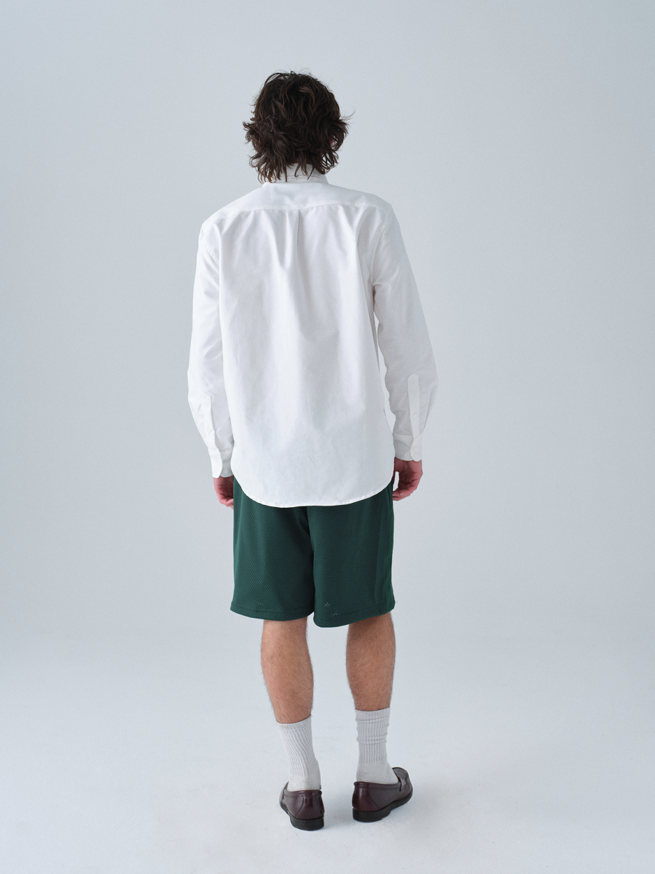Person wearing a white shirt and green shorts on a white background