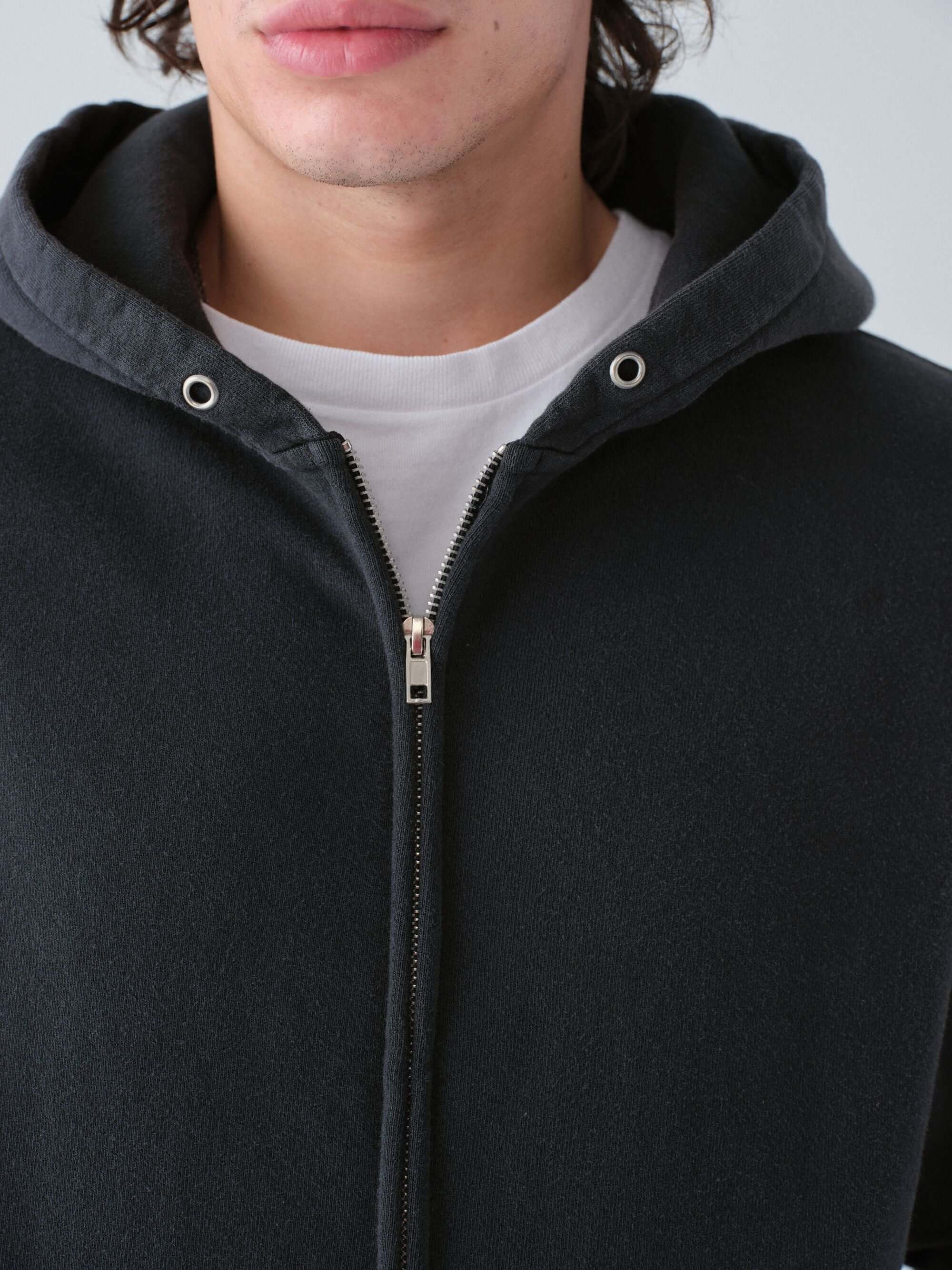 Close-up of a person wearing a Hanover zip hoodie in vintage black