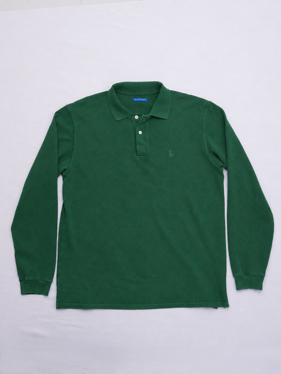 A Hanover green long-sleeve polo shirt with a two-button placket and a small embroidered logo on the left chest, laid flat on a light gray background.