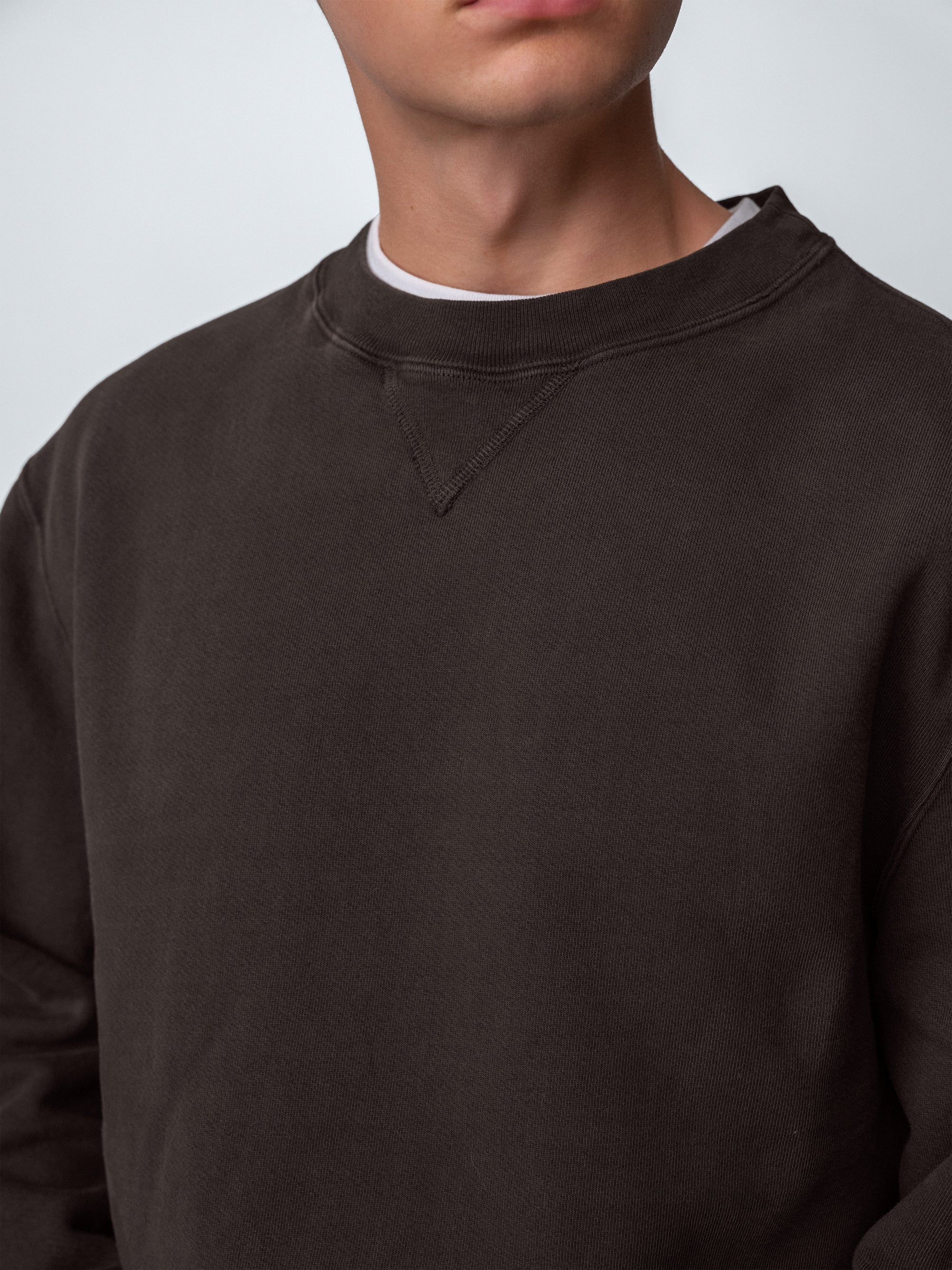 Detail of guy wearing Sunwashed Staple Crewneck in cacao