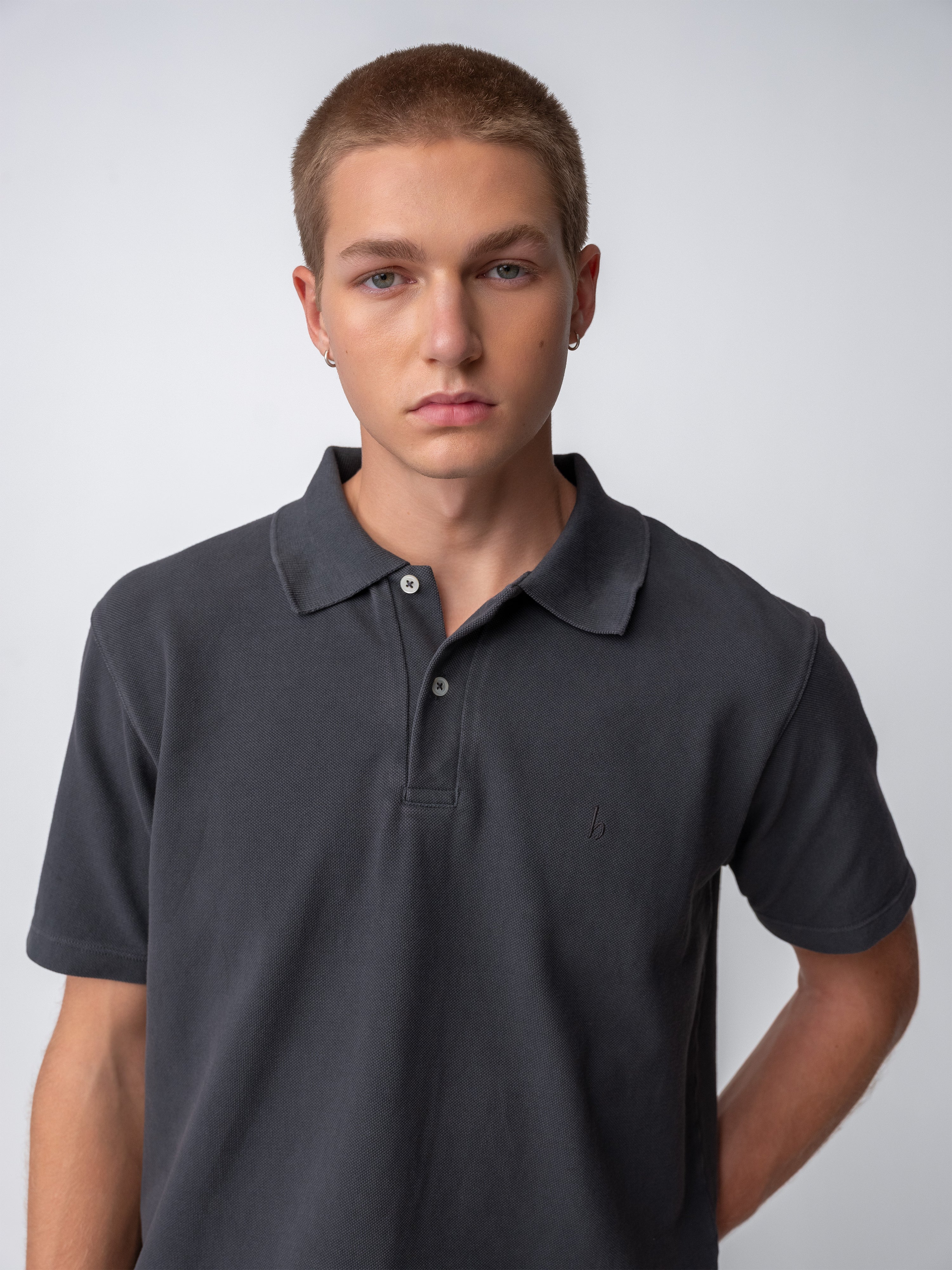 Model wearing a Sunwashed Staple Polo Shirt in dark color, featuring a classic collar and short sleeves.