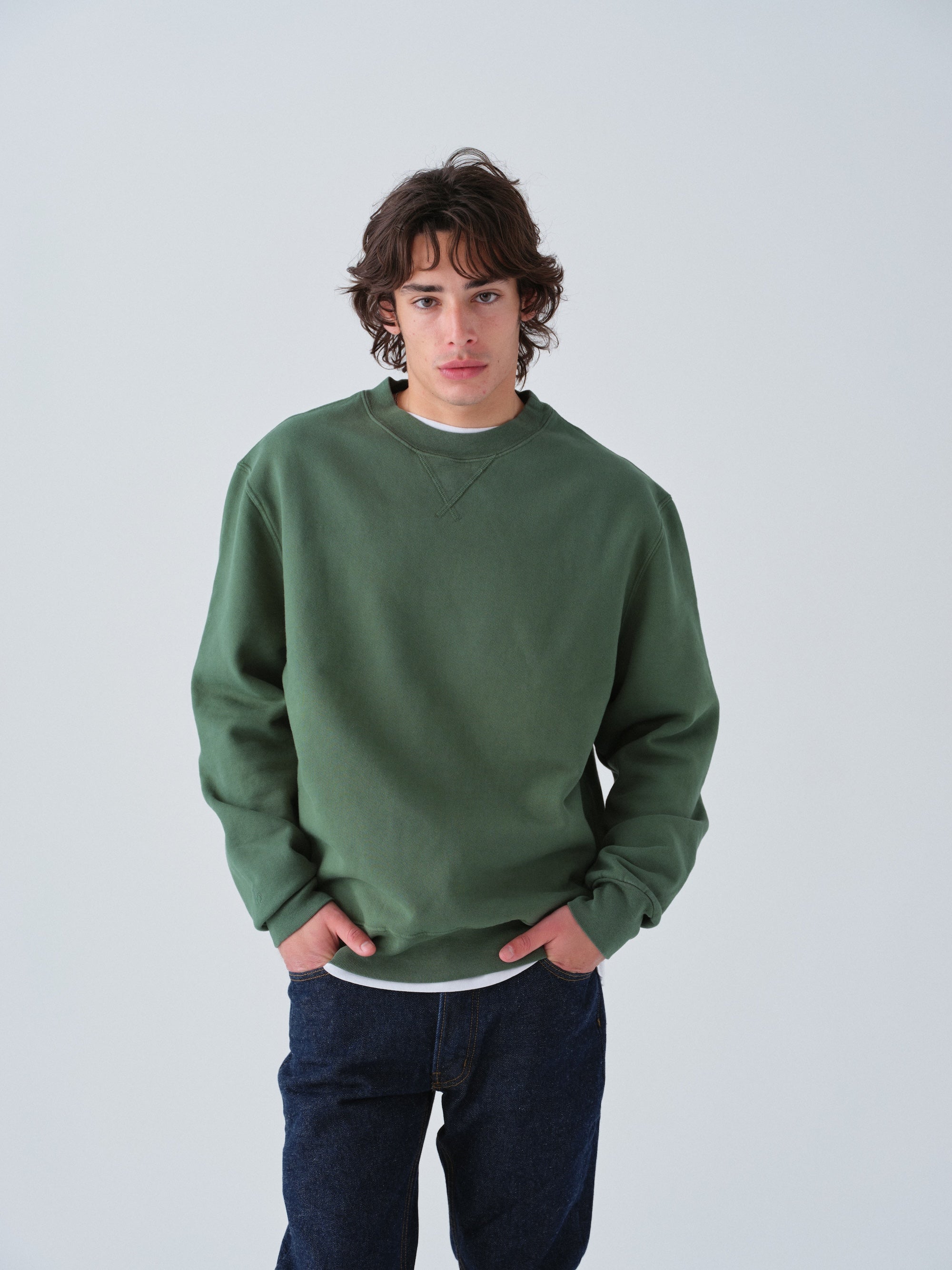 Guy wearing Sunwashed Staple Crewneck in hunter green torso view