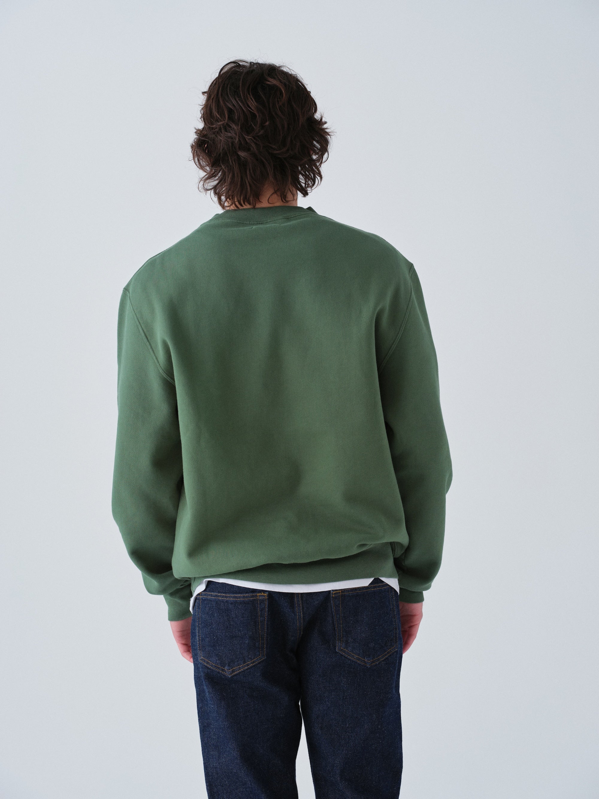 Guy wearing Sunwashed Staple Crewneck in hunter green back view
