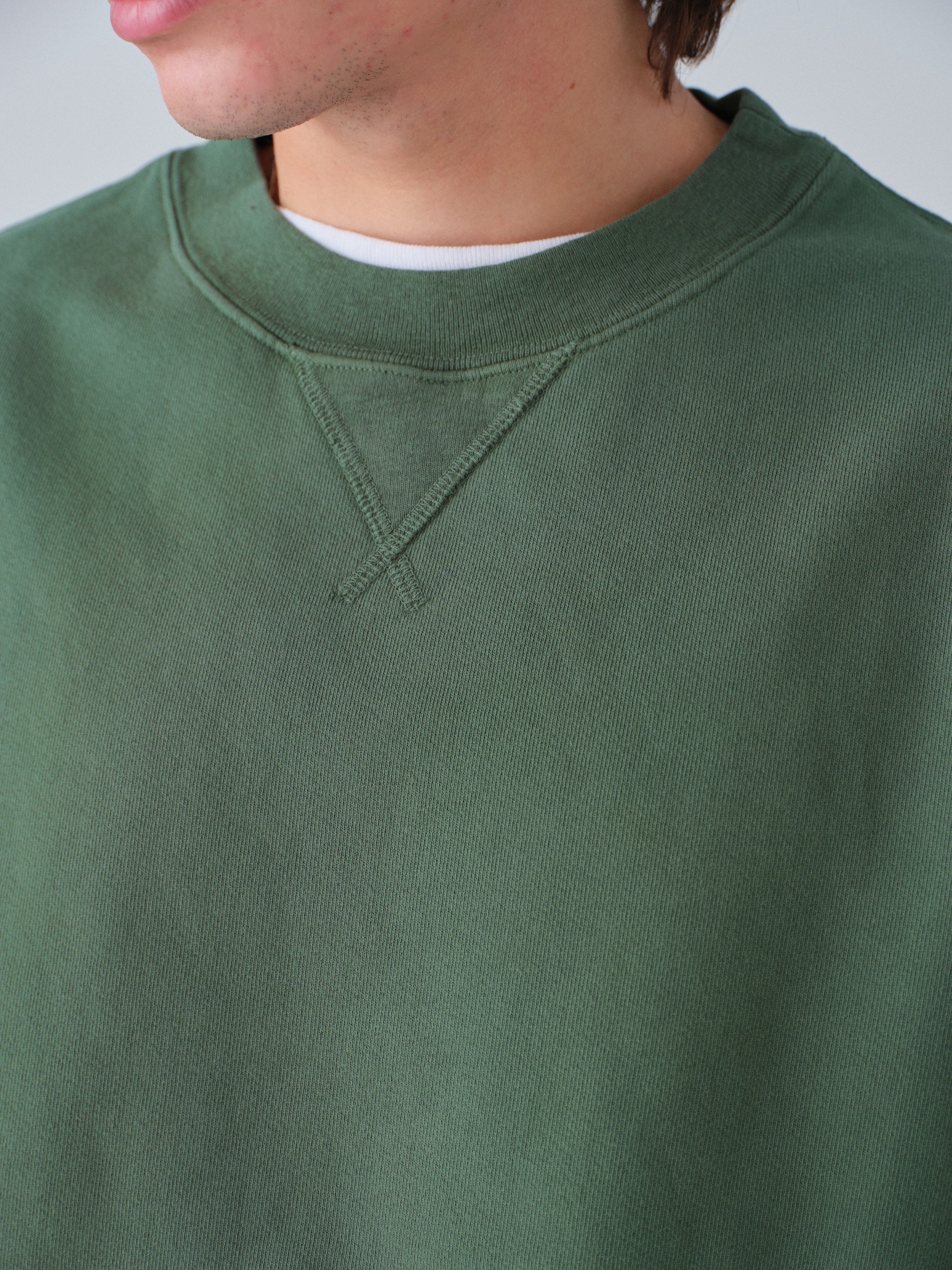Detail of guy wearing Sunwashed Staple Crewneck in hunter green