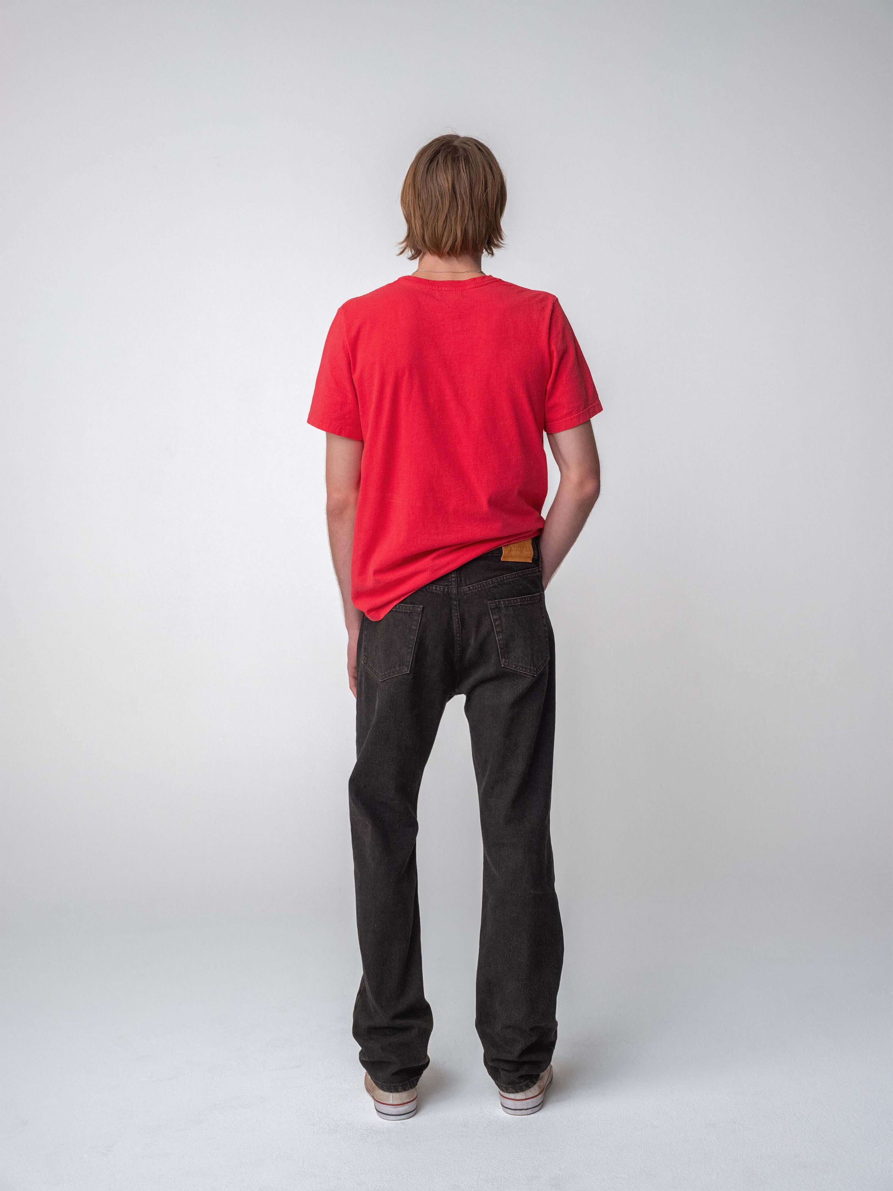Drift Jeans worn by a model in a red t-shirt, showcasing washed black denim from behind on a plain background.
