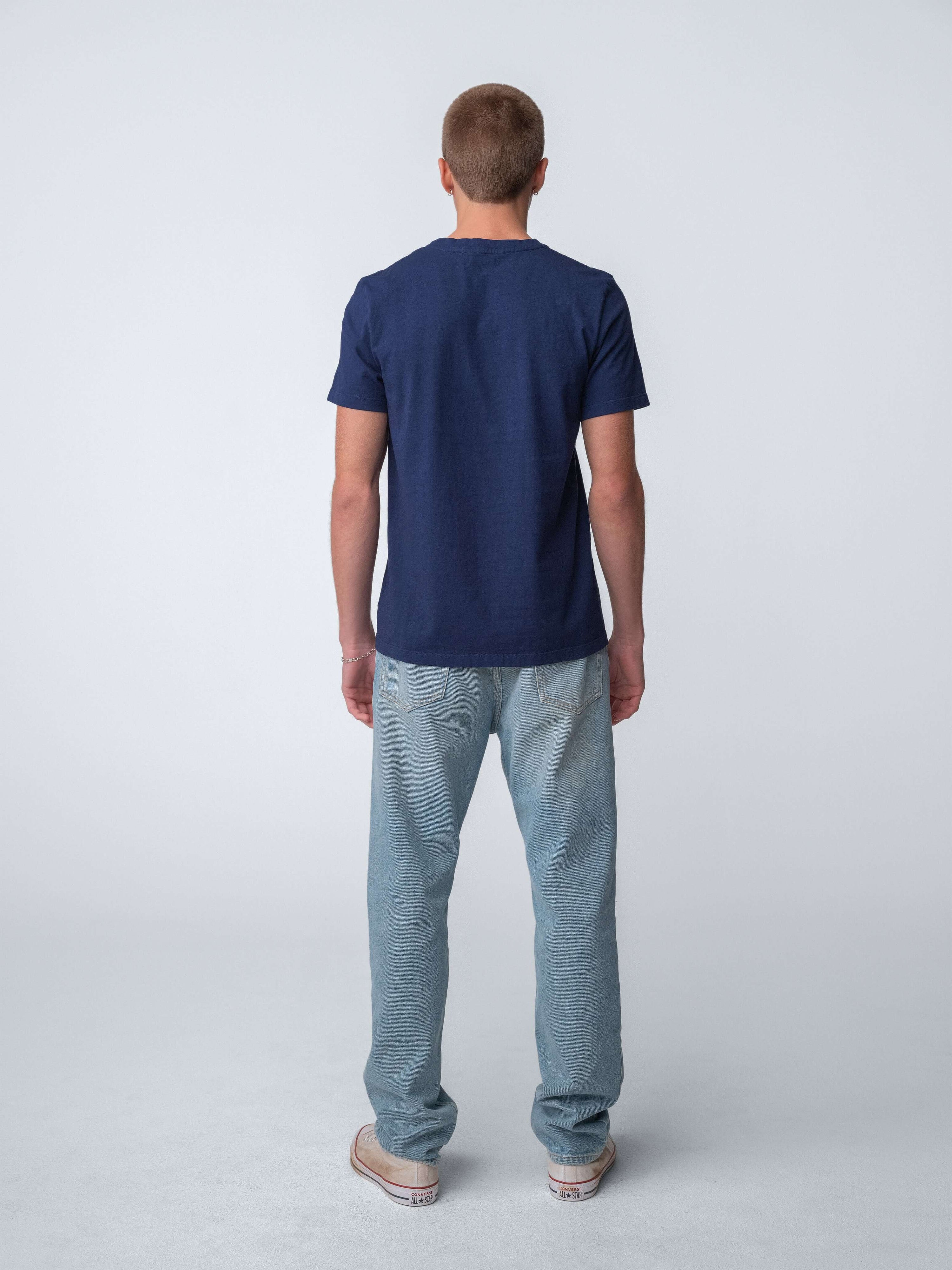 Man wearing Drift Jeans paired with a navy t-shirt, showcasing the Washed Blue denim style.